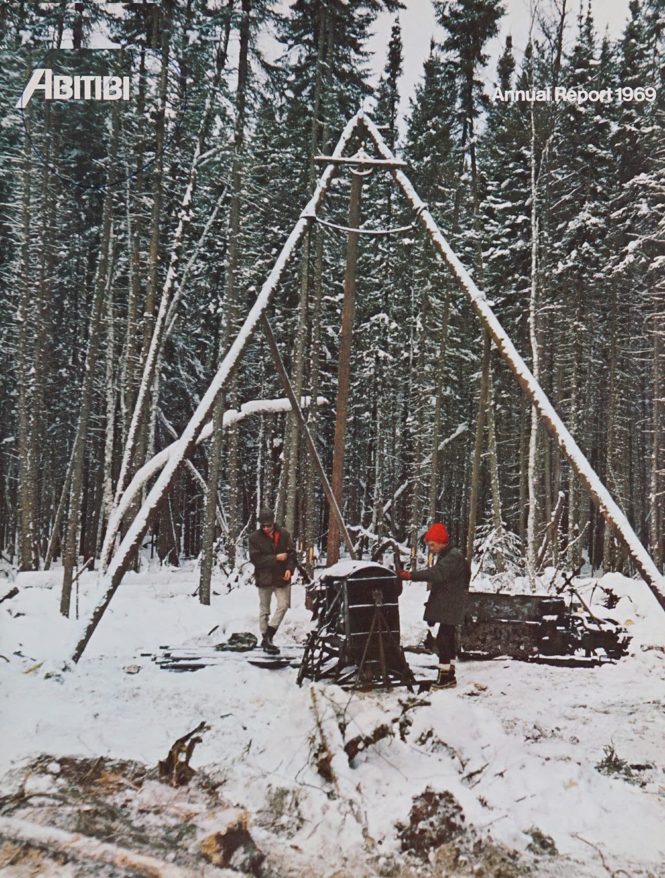 Two workers drilling under a snow-covered tripod.