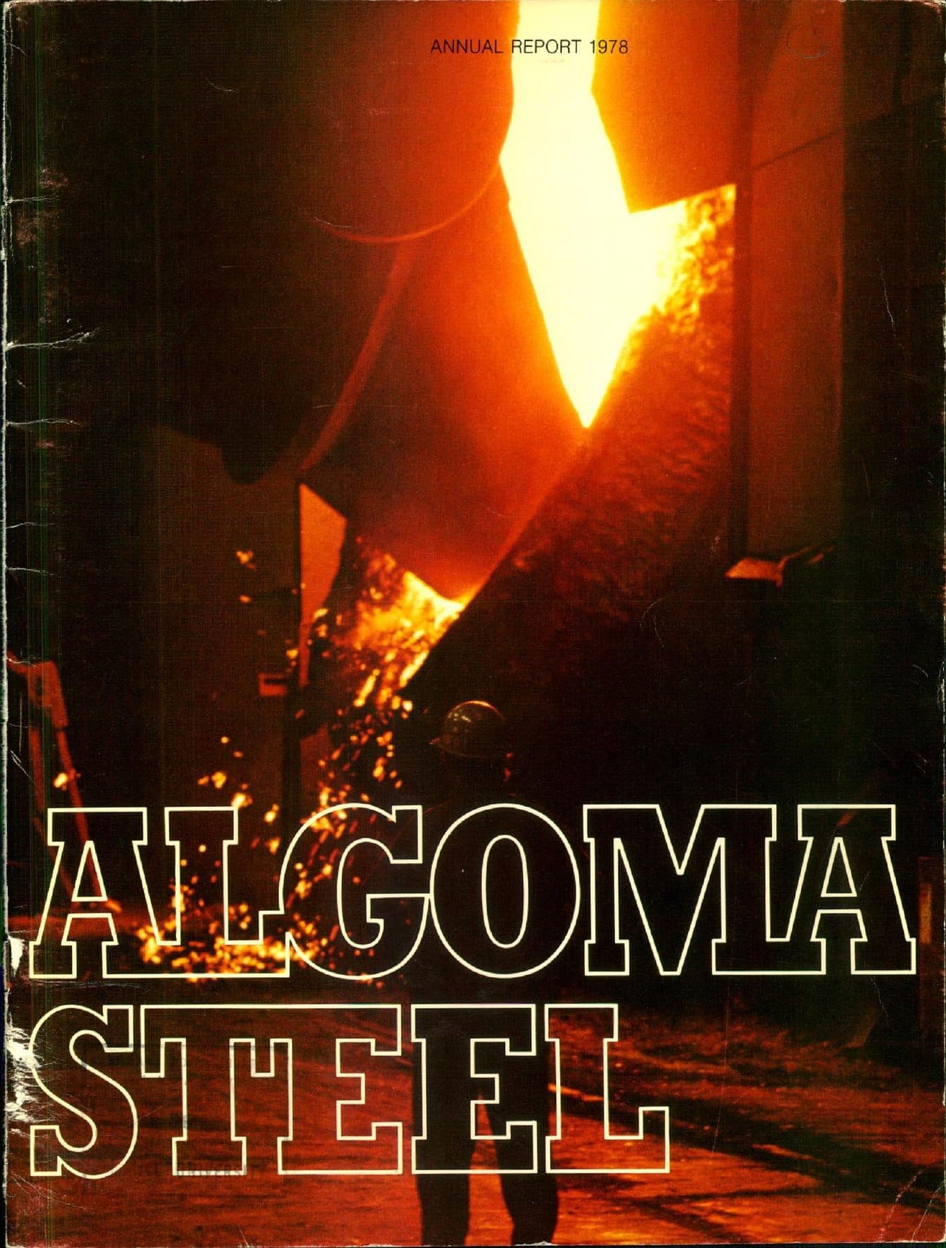 A steelworker under the ladle pour, sparks filling the mill.