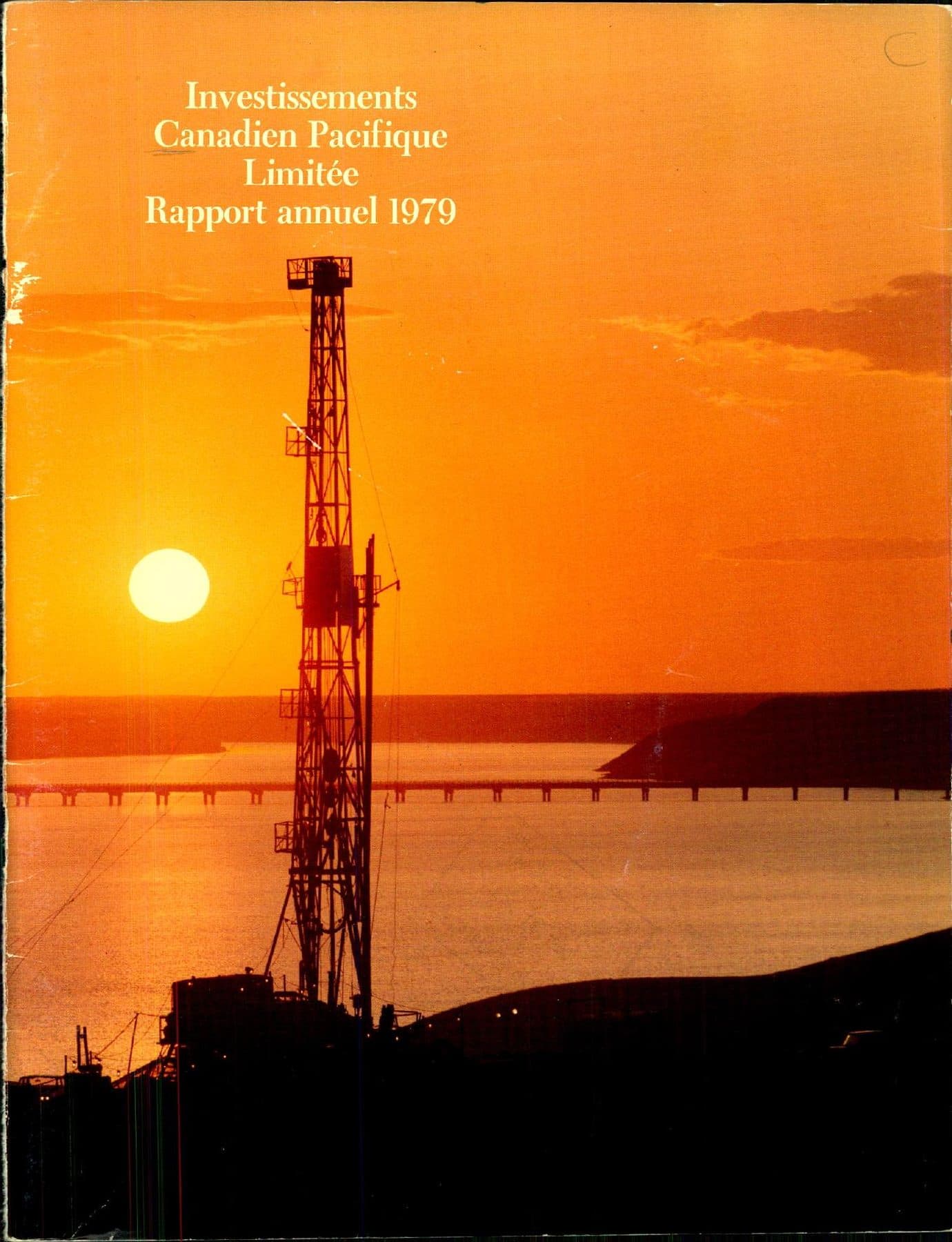 Sunset silhouette of a drill rig over water.